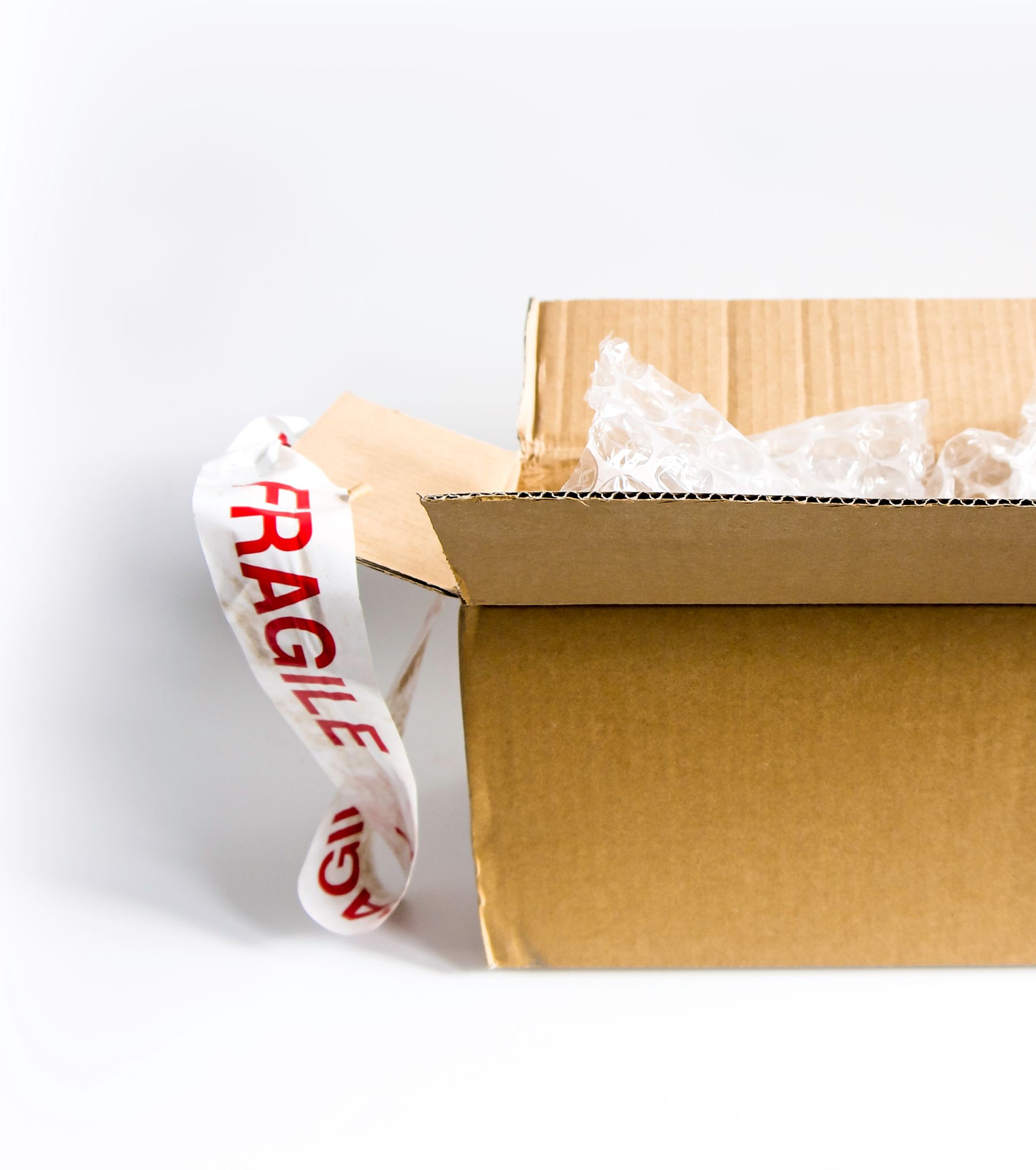 An open cardboard shipping box with protective bubble wrap and a fragile label.